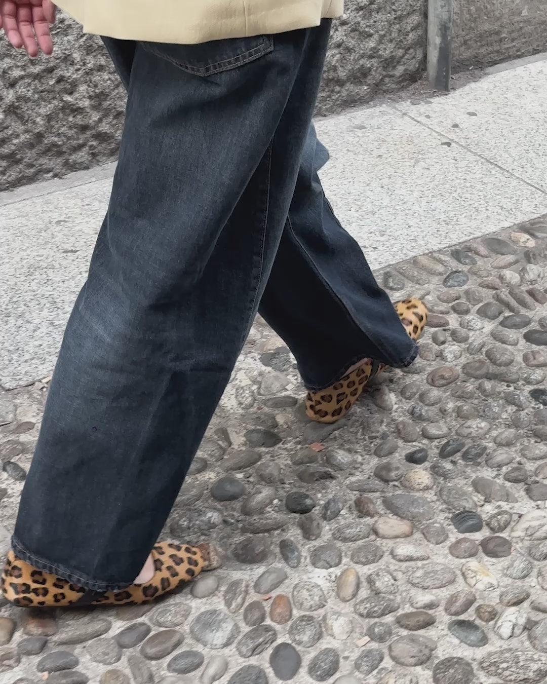Piedi della modella che camminano in strada indossando ballerine Hosis Milano in pelle cavallino leopardata